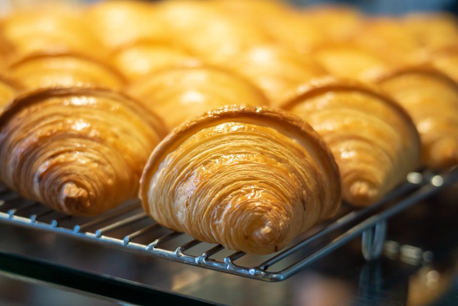 Close-up of golden, flaky croissants on a cooling rack, ready to be enjoyed.