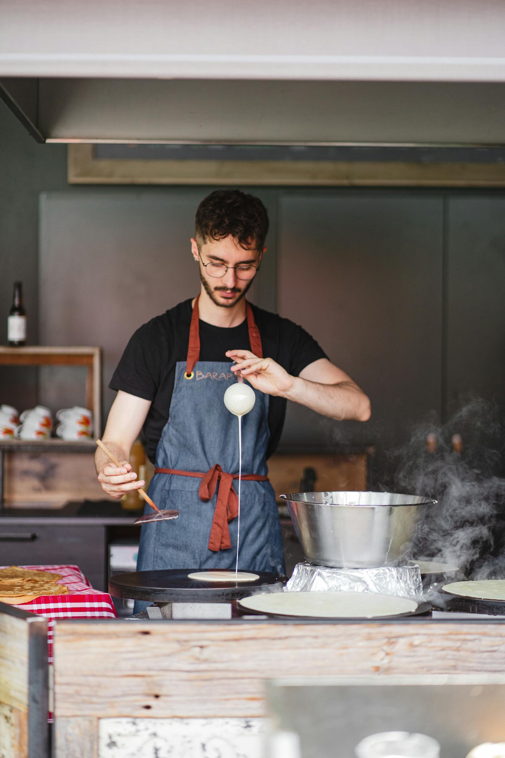 A chef carefully prepares crêpes in a cozy kitchen setting in Saint-Nazaire, France.
