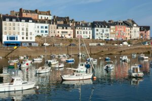 Vibrant harbor scene in Douarnenez, France, featuring colorful buildings and moored boats.